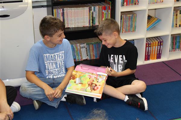  2 boys reading book together 